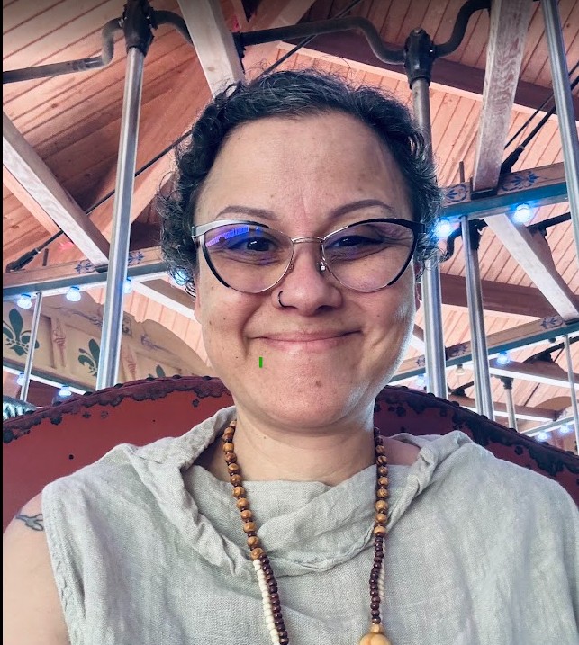 Camila, founder of The Eden Institute, smiling beneath the painted canopy of a carousel.